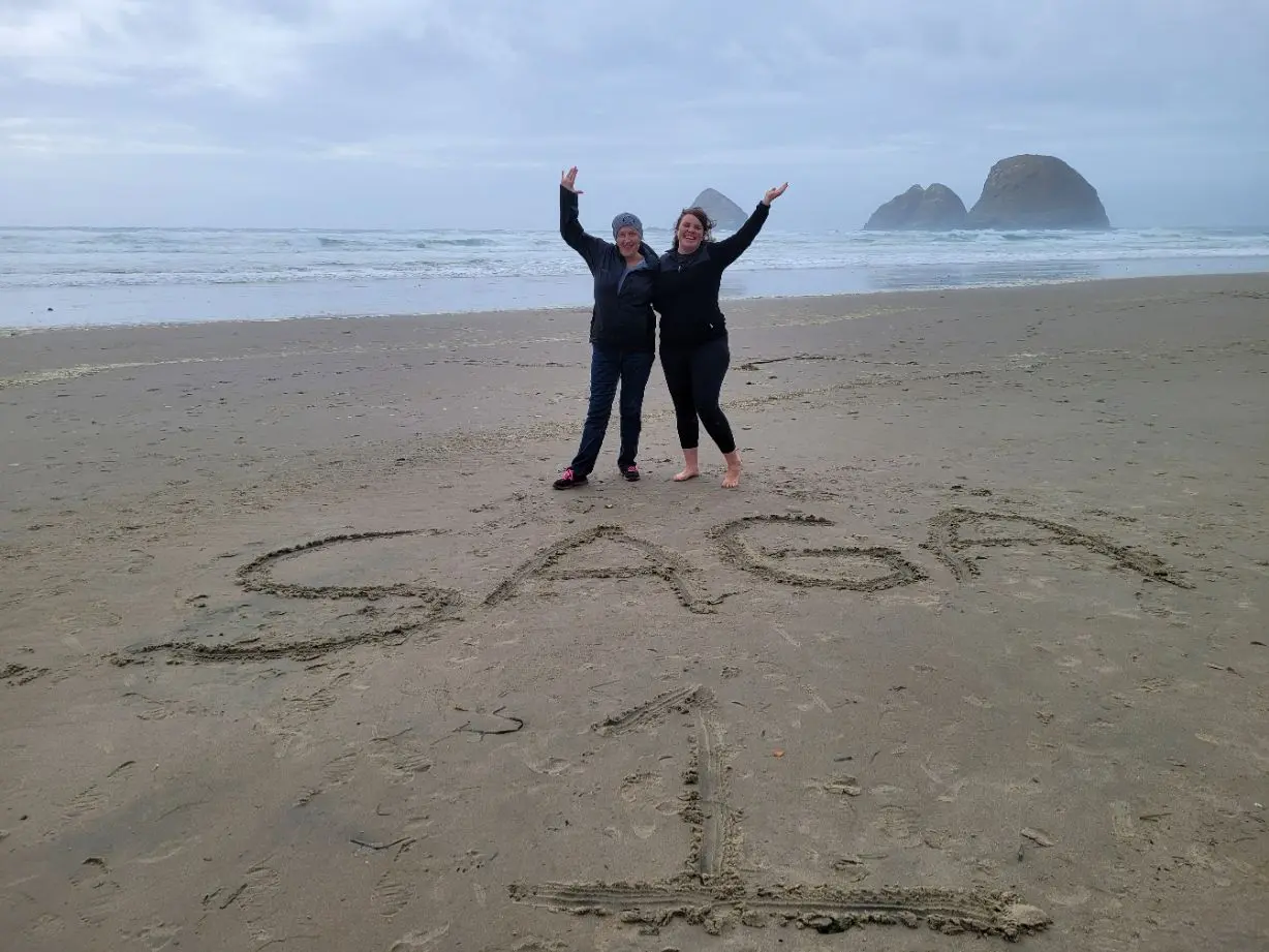 Two people standing on the beach with their arms in the air.