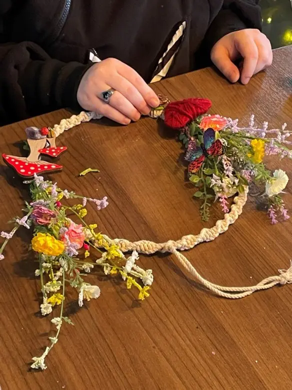 A person is making a flower crown on the table.