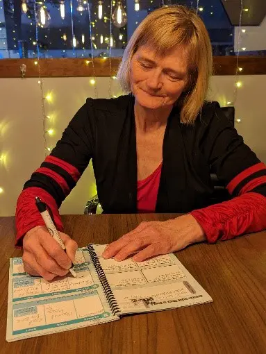 A woman sitting at a table writing on paper.